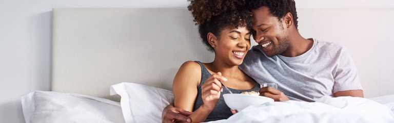 Married couple snuggle together and laugh while in their bedroom